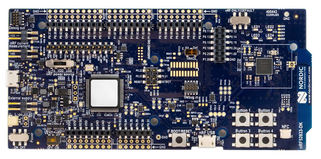 Photo du kit de développement nRF52833DK de Nordic d'une couleur de PCB Bleue, avec des broches, des boutons, des leds, le SoC nRF52833DK et un PCA10040